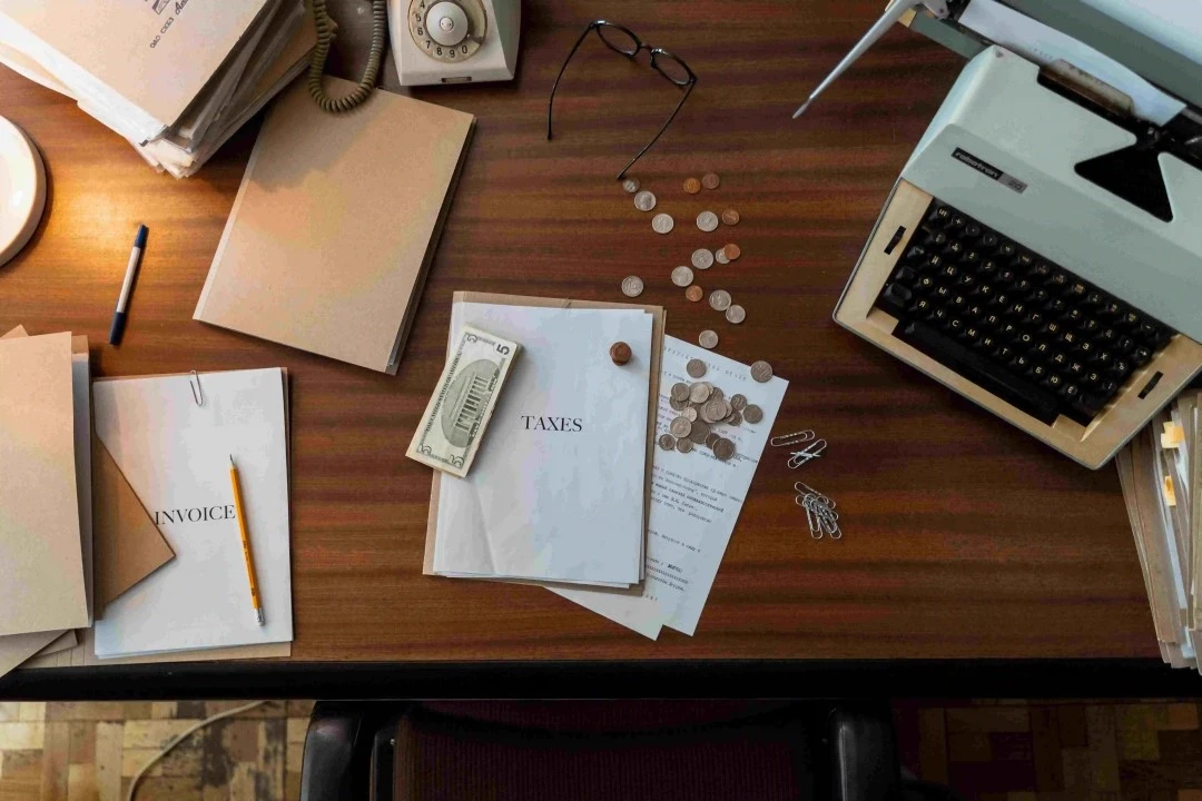 wooden desk background with a computer, money, phone and paper