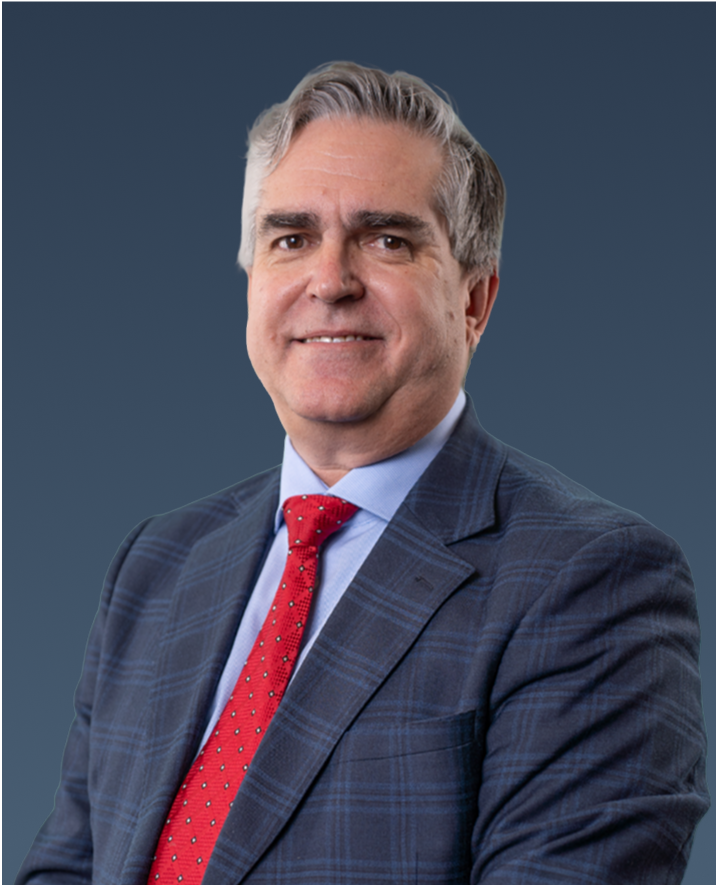 Professional portrait of a man with gray hair in a dark checkered suit and red tie, smiling.