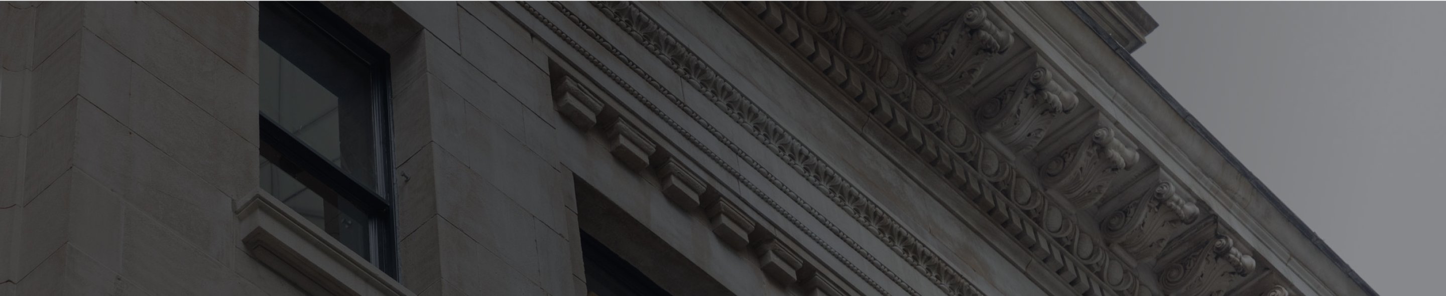 Close-up of a historic building façade with ornate stone carvings and the words ‘OPTIMIZE FINANCIAL GROUP’ engraved above the entrance.