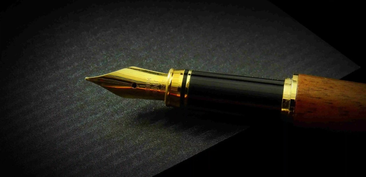 gold and black fountain pen on a desk 