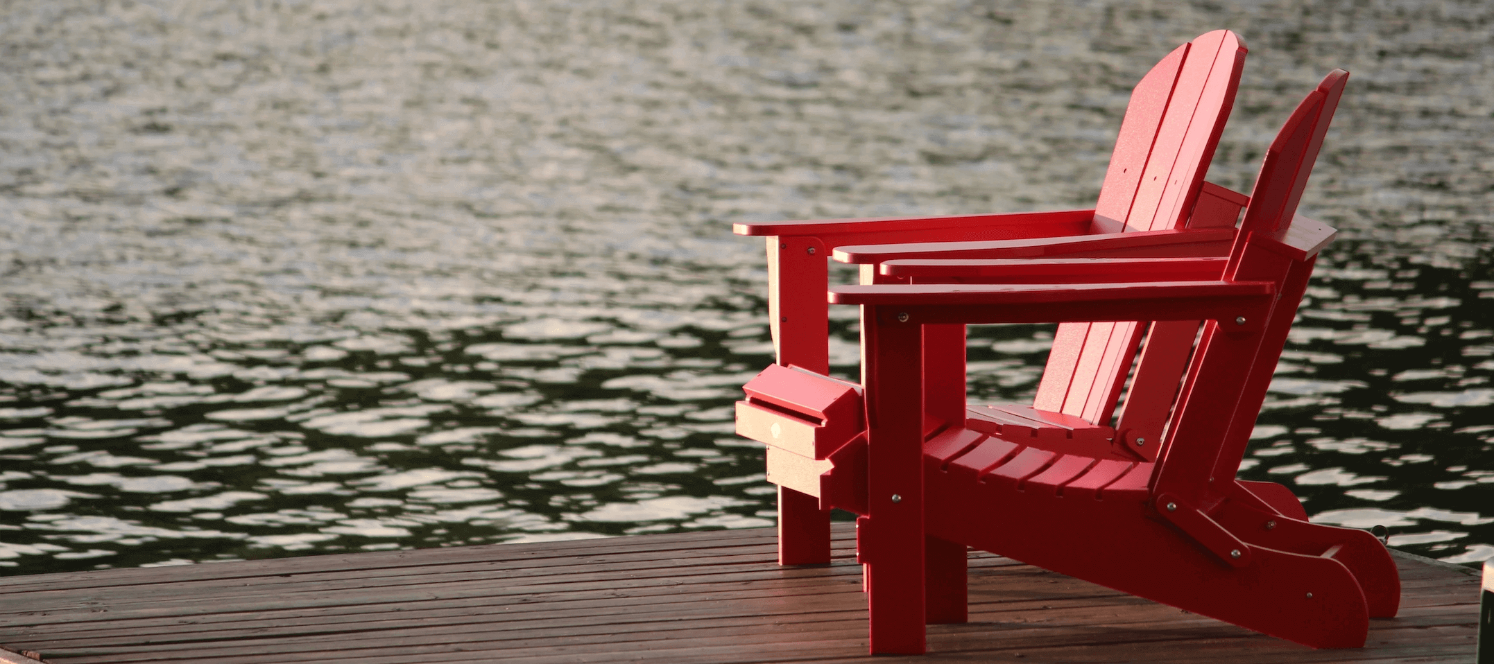Two red chairs on a lakeside patio 