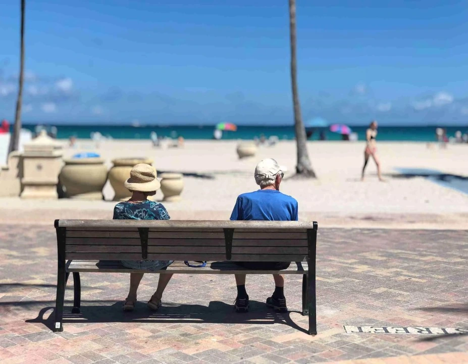 couple sitting on a bench by the beach
