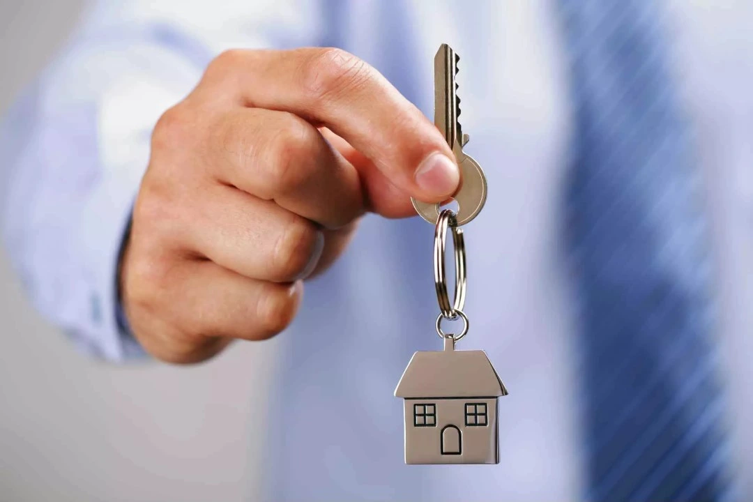 Hand of a man holding a keychain in shape of a house